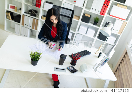 Beautiful young girl is working with documents in the office at the table. The girl highlights 41417135