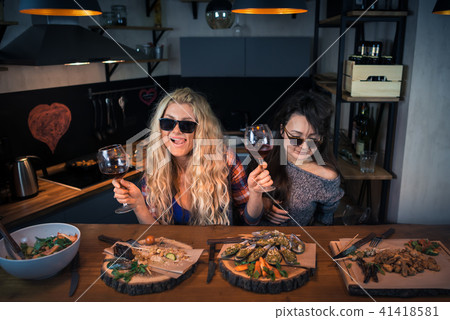 Two funny girlfriends smiles and holds glasses  41418581