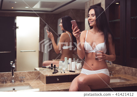 Carefree woman using mobile in bathroom Carefree woman using mobile in bathroom 41421412