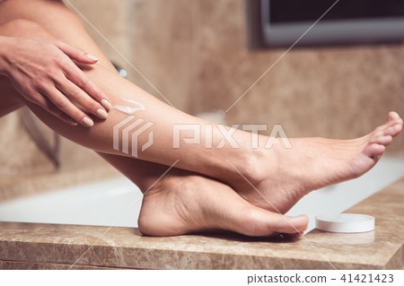 Girl sitting on bath and moisturizing body 41421423