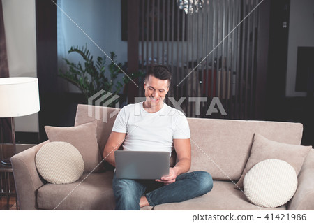 Happy young man using modern device on couch Happy young man using modern device on couch 41421986