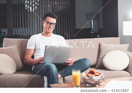 Joyful young man working on computer at home  41421987