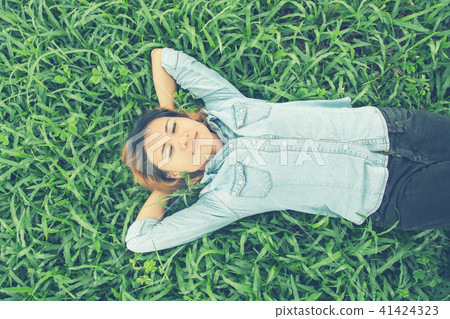 Young hipster woman lying down on grass. 41424323