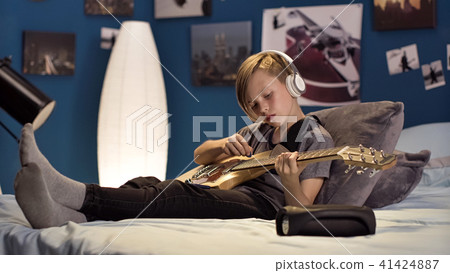 Boy in headphones learning song with guitar 41424887