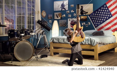 Expressive youngster playing guitar in bedroom 41424940
