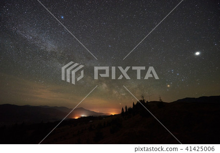 Fantastic mountains view at night. Fir-trees silhouettes against dark blue sky with sparkling stars 41425006