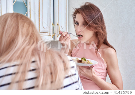beautiful vegetarian eating salad at home and listens to another woman beautiful vegetarian eating salad at home and listens to another woman 41425799