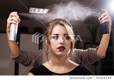 hairdresser fixing a coiffure of a model with two hair sprays 41426149