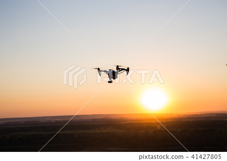 silhouette of drone, quadrocopter with photo camera flying in the sky. silhouette of drone, quadrocopter with photo camera flying in the sky. 41427805