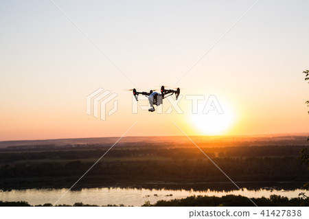 silhouette of drone, quadrocopter with photo camera flying in the sky. 41427838