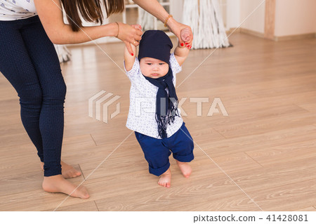 mother holding baby's hands to help him to walk. First step concept 41428081