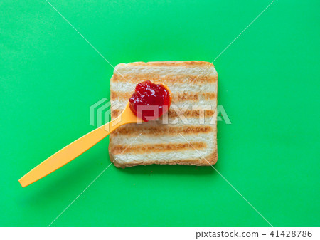 Slice of toast bread and tea spoon with jam 41428786