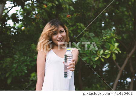 Young beautiful woman holding water at green park. Young beautiful woman holding water at green park. 41430461