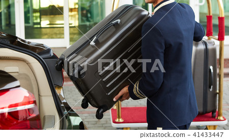 Bellboy taking baggage of guest from thee car to his room 41433447