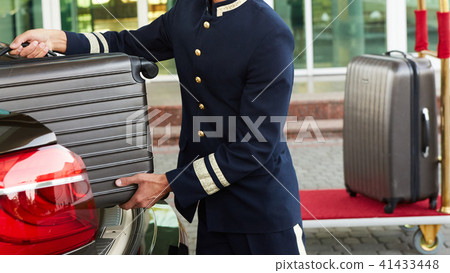 Bellboy taking baggage of guest from thee car to his room Bellboy taking baggage of guest from thee car to his room 41433448