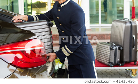 Bellboy taking baggage of guest from thee car to his room 41433456