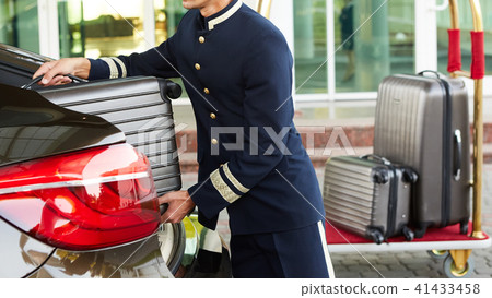 Bellboy taking baggage of guest from thee car to his room Bellboy taking baggage of guest from thee car to his room 41433458