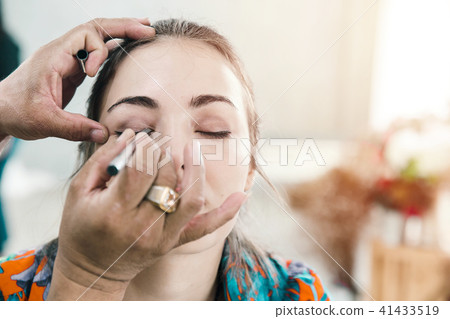 Model girl with Make up artist painting her eyes 41433519