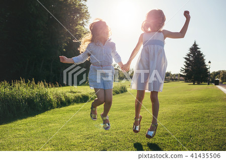 Two cheerful girls jumping against the sunset. 41435506