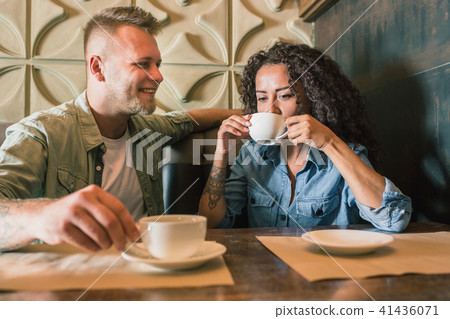 Happy young couple is drinking coffee and smiling while sitting at the cafe Happy young couple is drinking coffee and smiling while sitting at the cafe 41436071