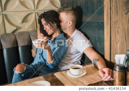 Happy young couple is drinking coffee and smiling while sitting at the cafe Happy young couple is drinking coffee and smiling while sitting at the cafe 41436134