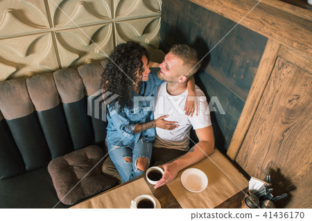 Happy young couple is drinking coffee and smiling while sitting at the cafe 41436170