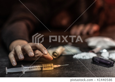Male junkie hand trying to grab syringe of heroine Male junkie hand trying to grab syringe of heroine 41440586