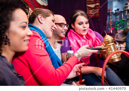Group of friends smoking hookah and drinking coffee in shisha lounge Group of friends smoking hookah and drinking coffee in shisha lounge 41440970