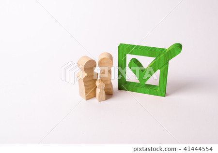 Wooden figures of people stand near the green tick 41444554