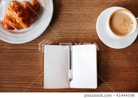 White opened notebook with cup of cappuccino and t 41444596
