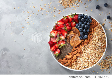 Fresh berries, almonds, oatmeal and granola in a plate with gray concrete background top view Fresh berries, almonds, oatmeal and granola in a plate with gray concrete background top view 41461569