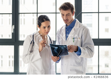 Two young dedicated doctors analyzing together a radiograph of the leg 41466636