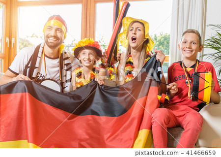 Whole family cheering for the German soccer team in front of TV 41466659