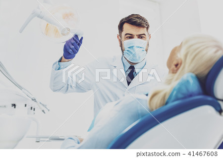 Delighted dentist treating his patient Delighted dentist treating his patient 41467608