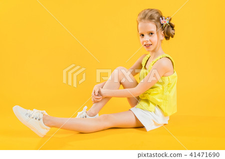 A teenage girl is sitting on a yellow background. A teenage girl is sitting on a yellow background. 41471690