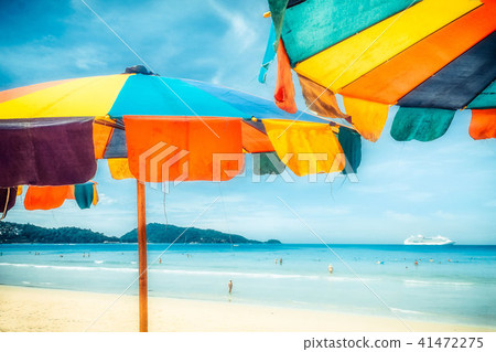 Two colorful sunshades in the beach on a sunny summer day. Summer background with colorful beach Two colorful sunshades in the beach on a sunny summer day. Summer background with colorful beach 41472275