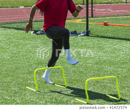 Female athlete stepping over mini hurdles in socks Female athlete stepping over mini hurdles in socks 41472574