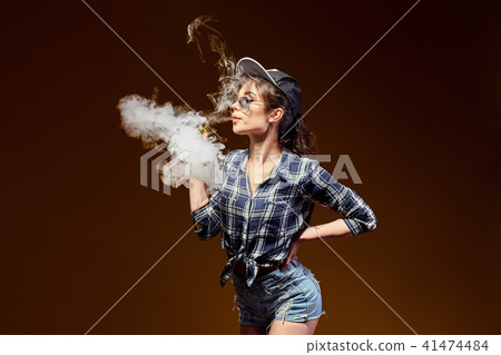 Woman standing and vaping in studio 41474484