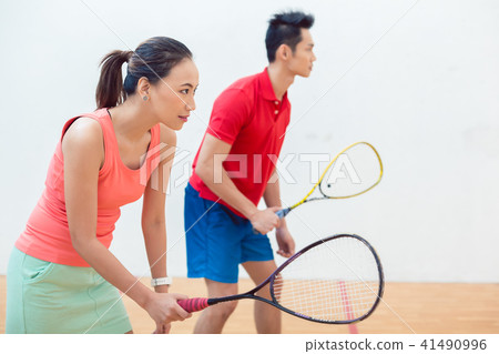 Competitive Chinese woman holding the racquet during a squash game Competitive Chinese woman holding the racquet during a squash game 41490996