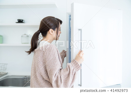 A woman who opens a refrigerator A woman who opens a refrigerator 41492973