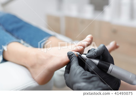 Doctor in gloves making procedure for foot with special equipment. Doctor in gloves making procedure for foot with special equipment. 41493075