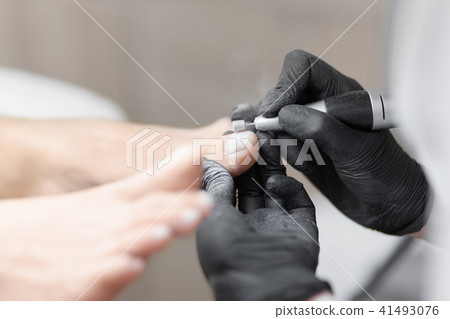 Doctor in gloves making procedure for foot with special equipment. Doctor in gloves making procedure for foot with special equipment. 41493076