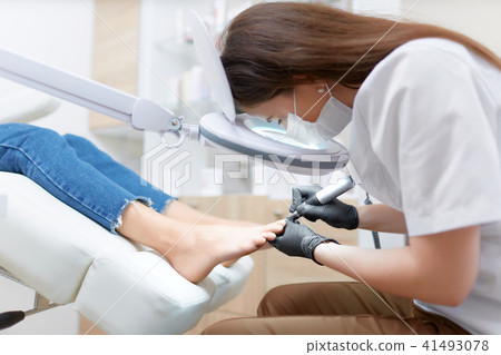 Podiatrist doctor in white making polish procedure for foot. Podiatrist doctor in white making polish procedure for foot. 41493078