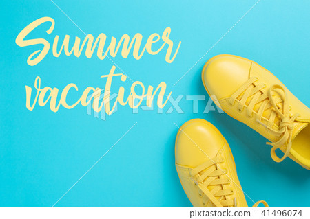 Pair of yellow shoes on blue background with inscription Summer vacation. 41496074
