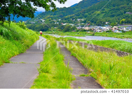 A woman holding an orange umbrella walking on the boardwalk on the Sakugawa river 41497010