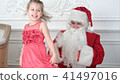 Santa Claus clapping his hands while pretty little girl dancing around him 41497016