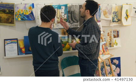 Two young men looking at paintings in art studio Two young men looking at paintings in art studio 41497130