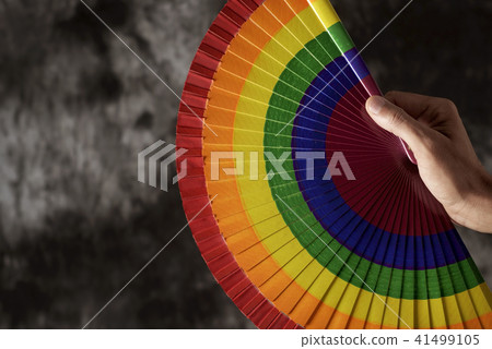 man with a rainbow-patterned hand fan. 41499105