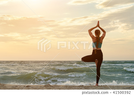 Girl on sea beach practicing yoga. Back view 41500392