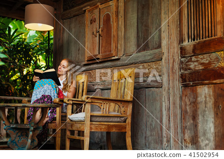 Young woman read paper book on outside veranda 41502954